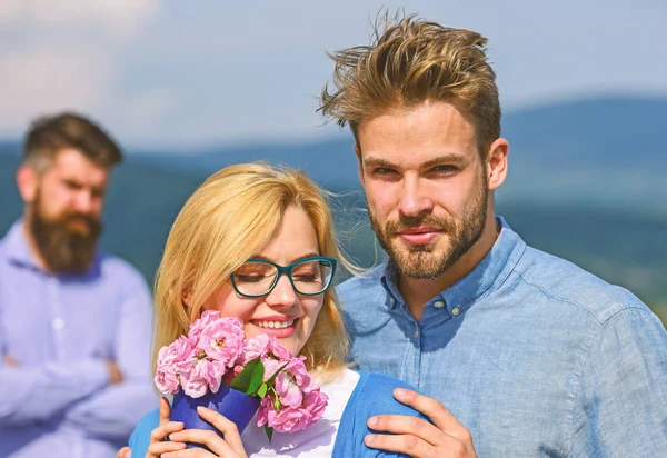 Casal apaixonado namoro enquanto homem barbudo ciumento assistindo esposa enganá-lo com amante. Conceito de infidelidade. Casal romântico namorados flores bouquet. Amantes abraços ao ar livre flertar relações românticas — Fotografia de Stock