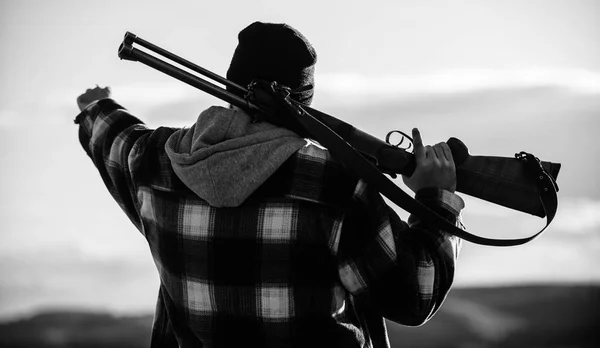 Άντρας κυνηγός δαπανούν ελεύθερο χρόνο κυνηγετικά. Κυνήγι αρρενωπός χόμπι αναψυχής έννοια. Βαρβαρότητα και αρρενωπότητας. Κυνηγός φέρουν όπλο τουφέκι στον ώμο πίσω όψη. Θηροφύλακας βάναυση τύπος άνθρωπος καπέλο φύση φόντο — Φωτογραφία Αρχείου