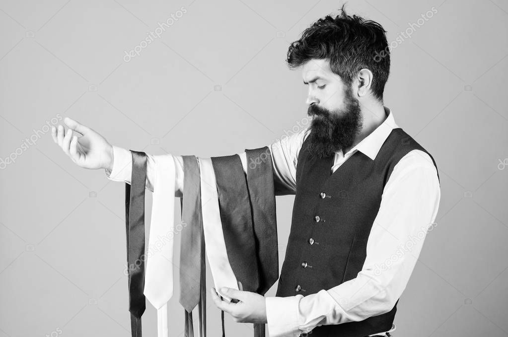 Tie the perfect for daily wear. Bearded man choosing neck tie. Brutal hipster holding colorful tie collection. Offering a huge selection of ties