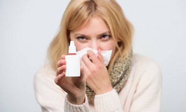 Relieving itchy nose. Cute woman nursing nasal cold or allergy. Sick woman spraying medication into nose. Treating common cold or allergic rhinitis. Unhealthy girl with runny nose using nasal spray