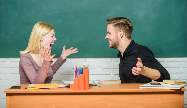 A partilhar boas notícias. Casal feliz estudando na sala de aula. Professor e professor sentado na mesa. Homem bonito e mulher bonita de volta à escola. Universitários ou universitários. Ensino médio — Fotografia de Stock