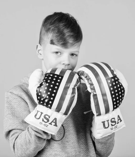 Начни боксерскую карьеру. Мальчик спортсмен носит боксерские перчатки с флагом США. Концепция американского боксера. Детский спортсмен, практикующий боксерские навыки. Боксерский спорт. К победе. Уверенный в своей силе — стоковое фото