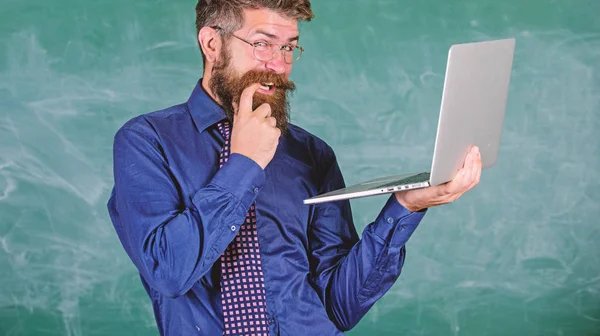 Peretas kehidupan sekolah. Guru Hipster memakai kacamata dan dasi memegang laptop surfing internet. Guru berjenggot licik pria modern laptop berselancar latar belakang papan tulis internet. Informasi yang menarik — Stok Foto