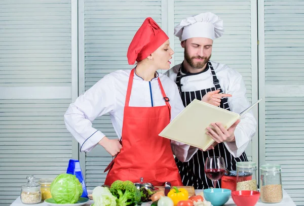 Kvinna kock och man lagar mat tillsammans. Kulinariska familjebegreppet. Par i kärlek matlagning hälsosamt recept. Amatör kock läsa bok recept. Förbättra matlagning skicklighet. Bokrecept. Hjälpsam matbok — Stockfoto