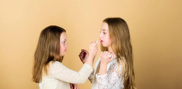 Knowledge without practice makes but half an artist. Small makeup artist giving beauty tutorial. Little make-up artist applying lipstick to girls lips. Cute beauty artist doing makeup to kid model