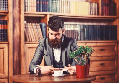 Olgun adam okuma. Olgun adam masada fincan çay ya da kahve ile oturuyor.