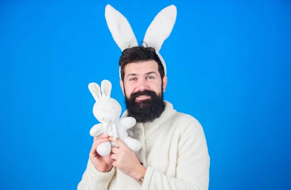 Guy bearded hipster cute gentle bunny long ears blue background. Respect for traditions. Easter bunny. Man wearing bunny plush suit. Funny bunny man with beard and mustache. Easter symbol concept