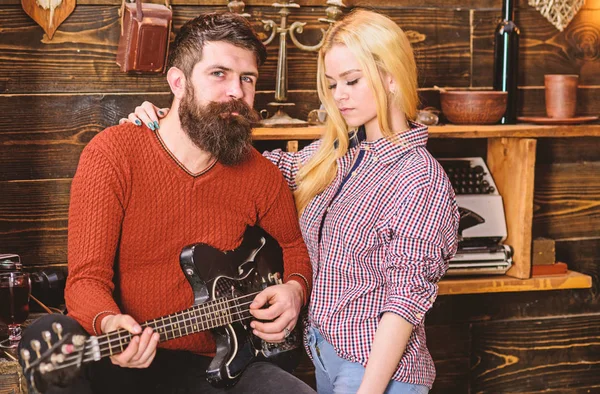 Concepto romántico de noche. Pareja enamorada pasar una velada romántica en un ambiente cálido. Señora y hombre con barba en caras de ensueño abrazos y toca la guitarra. Pareja en madera vintage interior disfrutar de la música de guitarra — Foto de Stock