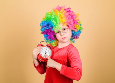 Hayat eğlencelidir. Mutlu çocukluk. Mutlu küçük kız. Uluslararası çocuk günü. Çocuk bakımı. Mutlu anlar. Çocuk çalar saati tutuyor. Bu kadar ciddi olmayı bırak. Kız sevimli oyuncu çocuk kıvırcık gökkuşağı peruk giymek