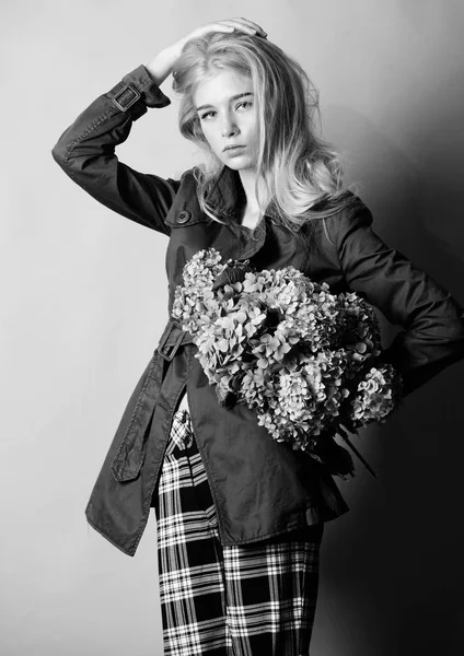 Kleding en accessoire. Meisje fotomodel draag jas voor de lente en herfst seizoen. Trenchcoat modetrend. Modieuze jas. Moet hebben concept. Blonde haren vrouw poseren jas met bloemen boeket — Stockfoto