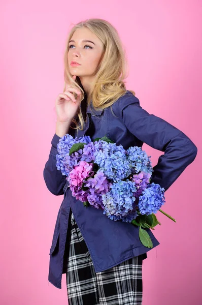 Must have concept. Clothes and accessory. Woman blonde hair posing coat with flowers bouquet. Fashionable coat. Girl fashion model wear coat for spring and autumn season. Trench coat fashion trend