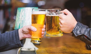 Şerefe kavramı. Taze bira fıçı bira ile köpük bardak. Erkek el ele tutuşur ile lezzetli bira dolu bardağı çubuk. Cuma Eğlence geleneği. Sayaç bar bira bardağı, arka plan defocused