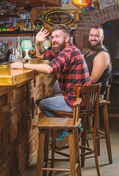 Friends relaxing in pub. Order drinks at bar counter. Hipster brutal bearded man spend leisure with friend at bar counter. Men relaxing at bar. Friday relaxation in bar. Friendship and leisure