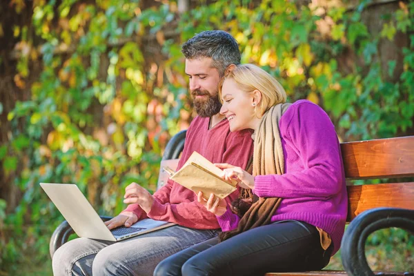 Use digital approach as well as books. Man and woman use different information storage. Couple spend leisure reading. Couple with book and laptop search information. Information source concept