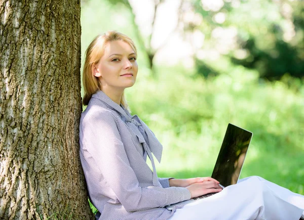 Arbete utomhus fördelar. Kvinna med laptop arbete utomhus Lean Tree. Minut för avkoppling. Flicka arbeta med laptop i parken sitta på gräs. Utbildningsteknik och Internet koncept. Naturmiljö kontor — Stockfoto