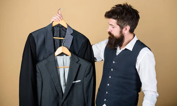 Being a tailor. Mens tailor. Hipster holding tailor made coats at department store. Bearded man choosing suit jacket in tailor shop. Clothing and tailoring — Stock Photo, Image