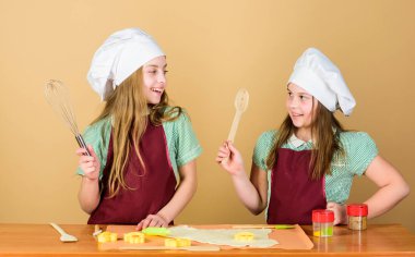 Zencefilli kurabiye pişiriyor. Kız kardeşler zencefil hamuru yla eğleniyorlar. En iyisi ev yapımı kurabiye. Çocuklar birlikte kurabiye pişiriyor. Çocuklar önlük ve şef şapkalar yemek. Aile tarifi. Aşçılık eğitimi. Anneler günü