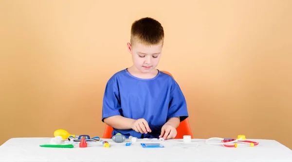 Medical education. Play game. Boy cute child future doctor career. Healthy life. Kid little doctor sit table with stethoscope and medical tools. Medicine concept. Health care. Medical examination — Stock Photo, Image