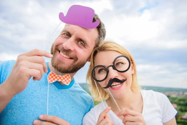 Photo booth props. Man with beard and woman having fun party. Add some fun. Making funny photos birthday party. Just for fun. Humor and laugh concept. Couple posing with party props sky background