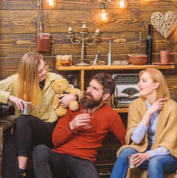 Man en dames op Gelukkige gezichten bespreken en drinken Glühwein. Vrienden doorbrengen vrijetijdsbesteding in gezellige interieur. Soulmates concept. Vrienden hebben plezier, spreken en het drinken van warme dranken in houten interieur — Stockfoto