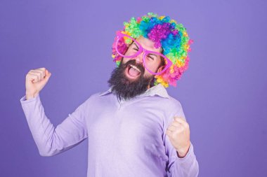 Eğleniyor. Tatil eğlenceli ve karnaval kavramı. Adam giyim renkli peruğu ve menekşe arka plan üzerinde komik gözlük sakallı. Palyaço ve sirk. Parti eğlenceli. Deli olmanın tadını çıkarın. Kendinizi ifade çekinmeyin