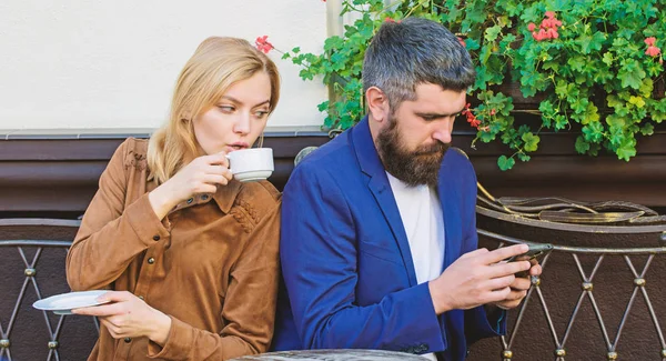 lack of live communication. First meet of girl and mature man. woman and man with beard relax in cafe. Brutal bearded hipster and girl drink coffee. Morning coffee. Couple in love on romantic date