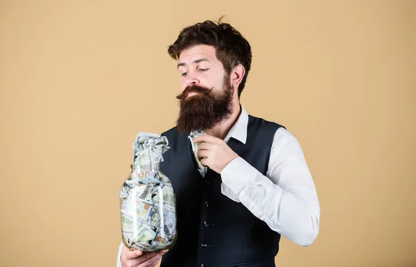 Taking money for doing business. Businessman taking money out of glass jar. Bearded man putting investing money in startup business. Business savings. Business and finance — Stock Photo, Image