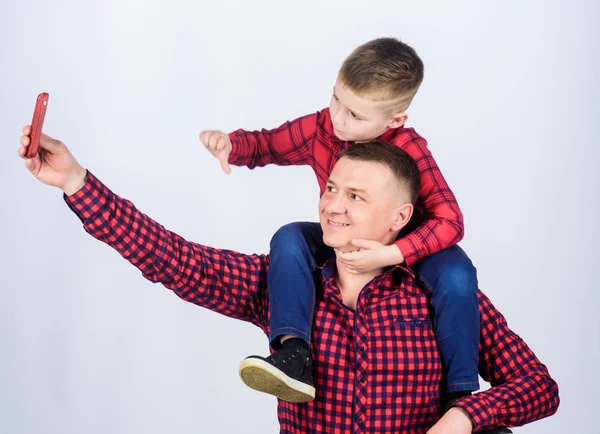 Tomándose selfie con su hijo. Niño montado en los hombros de los papás. La felicidad es el padre del niño. Divirtiéndose. Día de los Padres. Padre ejemplo de noble humano. Padre pequeño hijo rojo camisas familia look traje — Foto de Stock