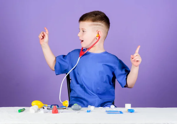 Concepto de medicina. Salud. Examen médico. Educación médica. Juega a juego. Niño lindo niño futuro médico carrera. Vida sana. Pequeño doctor sentado mesa con estetoscopio y herramientas médicas —  Fotos de Stock