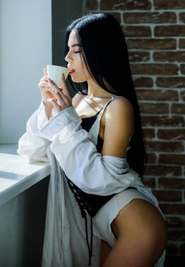 Çekici kadın iç çamaşırı evde rahatlatıcı. Tutkulu gizemli aşık. Mükemmel kahve zamanı. Ama önce kahve. Sabah güneşışığının tadını çıkarıyorum. Şehvetli kız seksi göğüsler pencere kenarında kahve içme