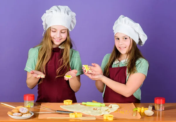 Dessert made with care. Small children baking dessert together. Little girls cooking sweet baked pastry dessert in kitchen. Adorable cooks preparing cutout cookies cooked dessert
