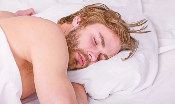 Cuánto sueño necesitas en realidad. Un hombre guapo yacía en la cama. Duerme una cantidad adecuada y constante de sueño todas las noches. Consejos de expertos para dormir mejor. Barbudo hombre durmiendo cara relajante en la almohada — Foto de Stock