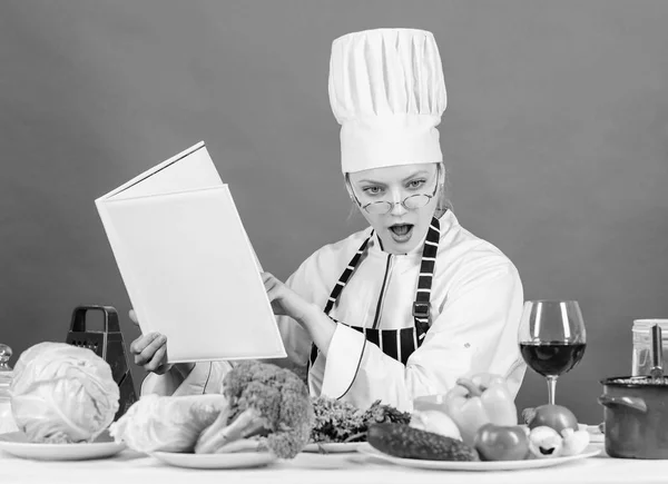 Girl read book best culinary recipes. Culinary education concept. Female in hat and apron knows everything about culinary arts. Improve cooking skill. Culinary expert. Woman chef cooking healthy food — Stock Photo, Image