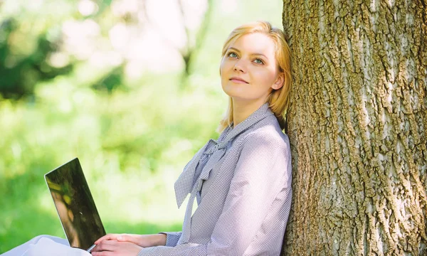 Жінка з ноутбуком працює на відкритому повітрі худе дерево. Хвилина для відпочинку. Дівчина працює з ноутбуком у парку сидить на траві. Освітні технології та концепція Інтернету. Офіс природного середовища. Робота на відкритому повітрі переваги — стокове фото