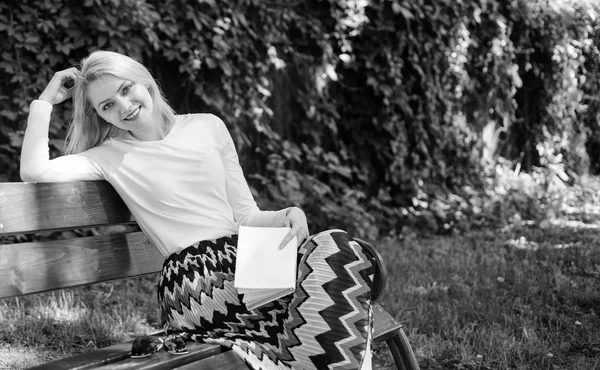 Femme heureuse blonde souriante prendre une pause détente dans le jardin lecture de poésie. Lady profiter de la poésie dans le jardin. Amuse-toi bien. Banc de fille assis relaxant avec livre, fond vert de la nature. Poème romantique — Photo