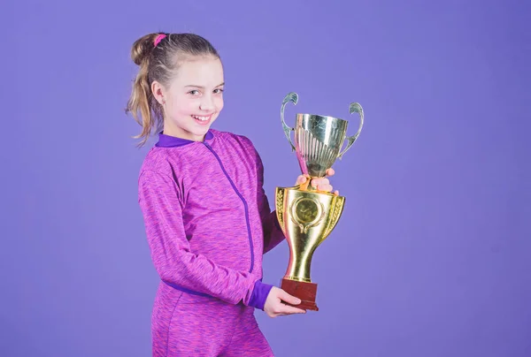 Adorable cup winner. Small girl holding silver cup. Little child with cup shaped sports trophy. Cute athlete being awarded with cup. Declaring the winner, copy space