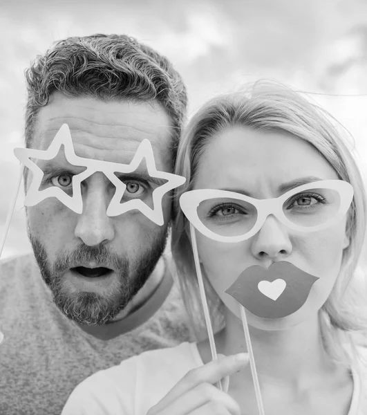 Perfect for photo fun. Funny couple in party photobooth props. Couple in love enjoy party time on cloudy sky. Pretty woman and bearded man wear fake glasses accessories. Photo booth party celebration