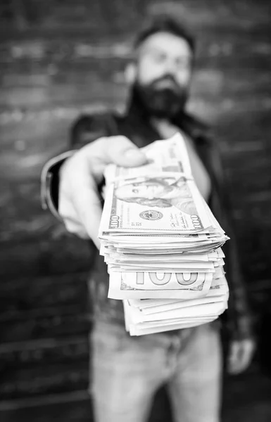 Man give cash money bribe. Richness and wellbeing. Mafia business. Man brutal bearded hipster wear leather jacket and hold cash money. Illegal profit and black cash. Guy mafia dealer with cash profit