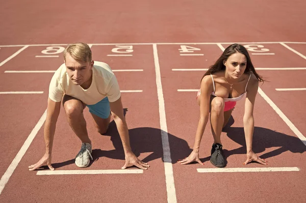 Concepto de fuerzas iguales. Hombre y mujer de baja posición de inicio corriendo estadio de superficie. Competencia o raza de género. Deportista más rápido lograr la victoria. Desafío deportivo para parejas. Todo el mundo tiene oportunidad — Foto de Stock