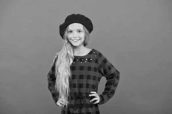 Inspiration de style béret. Portez un béret comme une fille de la mode. Enfant petite fille mignonne avec de longs cheveux blonds posant en chapeau de béret et robe à carreaux fond rouge. Accessoire de béret à la mode pour femme — Photo