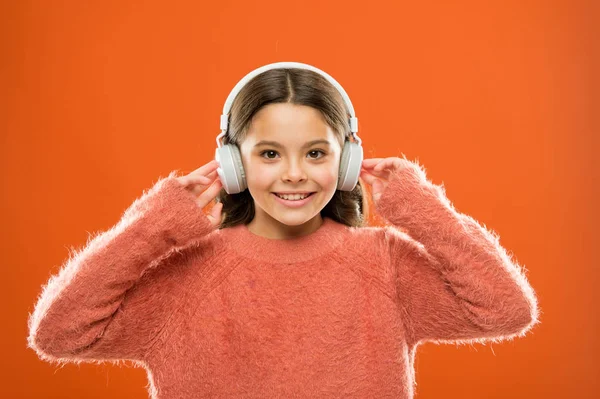 Med hjälp av trådlös Bluetooth teknik. Litet barn lyssnar på musik i Bluetooth stereohörlurar. Liten flicka bär moderna Bluetooth-hörlurar. Ansluta Bluetooth-headset till hennes musikspelare — Stockfoto