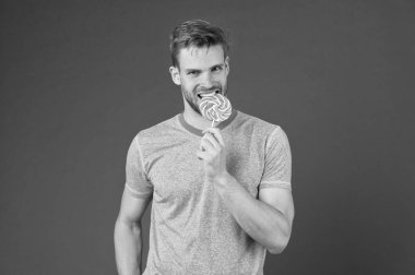 Sakallı adam Lolipop sever. Tatlıya kavramı. Şeker sağlık için zararlı. Adam lolipop şeker menekşe arka plan tutun. Adam yakışıklı maço büyük renkli tatlı lolipop yemek. Çocukluk tadına