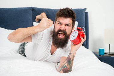 Neden her sabah erken kalkmalısın? Uyanma zamanı. Erken yükselen sağlık yararları. Erken uyanma hazırlamak ve zamanında olmak için daha fazla zaman verir. Hipster sakallı adam çalar saat ile yatakta yatıyordu