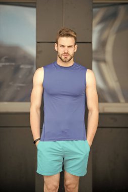 Stadyumda adım sayacı ile spor antrenmanı. Spor aleti konsepti. Spor ekipmanları ve şehir geçmişi olan sert yüzlü bir sporcu. Sporcu fitness takip cihazı ya da adım sayacı. Sıkı çalışmaya hazır.