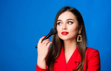 Profesyonel makyaj fırçası olan seksi bir kadın. Mücevher küpeleri. Kırmızı ceketli kız. Güzellik ve moda. Saç güzellik salonu ve kuaför salonu. Bir kadının moda portresi. kopyalama alanı. Havalı ve seksi