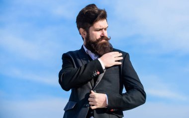 Çok doğru. İş adamı sakallı, gökyüzü geçmişi olan. Kusursuz kıyafet. Erkek takım elbisesi ceketi ayarlıyor. Erkek moda erkek giyimi. Moda modası. Erkek sakalı ve bıyığı resmi kıyafetler giyer.