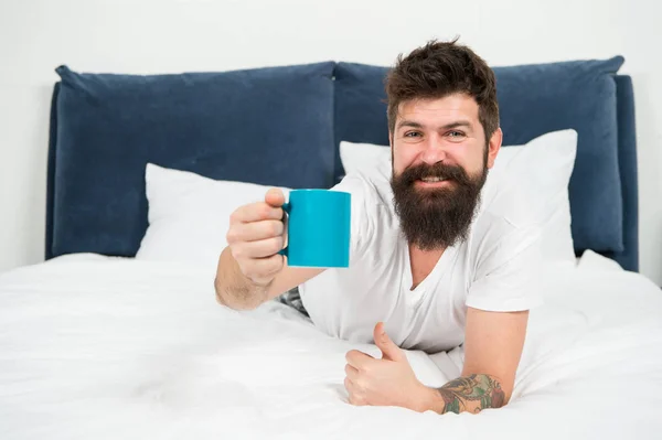 Voici votre café du matin. homme endormi brutal dans la chambre. mâle mature avec barbe en pyjama sur le lit. endormi et réveillé. énergie et fatigue. heureux homme barbu boire le café du matin. Tôt le matin — Photo