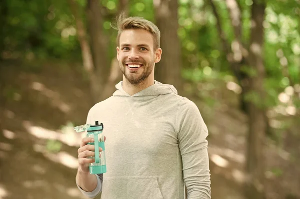 Atleta satisfecho cara celebrar botella cuidado hidratación cuerpo después del entrenamiento. Refrescante bebida de vitaminas después de un gran entrenamiento. El aspecto atlético del hombre sostiene la botella de agua. Atleta beber agua después de maratón — Foto de Stock