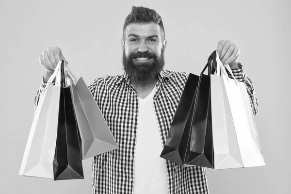 Hacer compras más alegres. Hombre barbudo hipster cara alegre llevar bolsas de compras de papel sobre fondo amarillo. Disfruta de compras rentables ofertas negro viernes. Compras con descuento disfrutar de compra —  Fotos de Stock