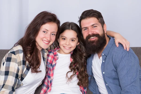 Dost canlısı aile fotoğraf aile albümü için poz kanepede oturup. Anne baba ve kızı kanepede rahatlatıcı gülümsüyor. Aile bağları kavramı. Tek çocuklu tipik bir aile. Aile hafta sonunu birlikte geçiriyor — Stok fotoğraf